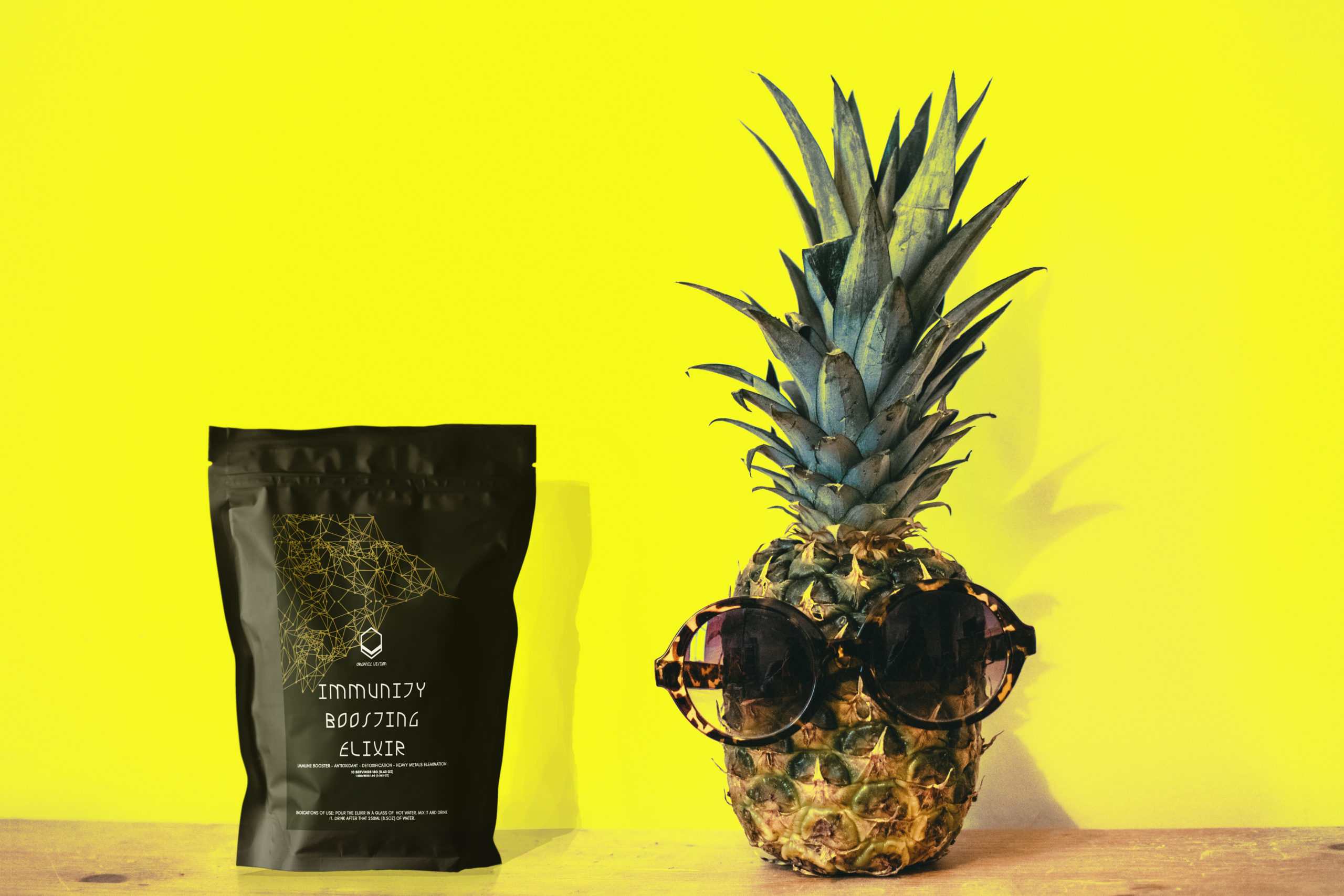 Immunity boosting elixir and pineapple near a yellow background